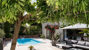 Un espace piscine doté d’une terrasse en bois, de mobilier d’extérieur et d’un arbre offrant de l’ombre.