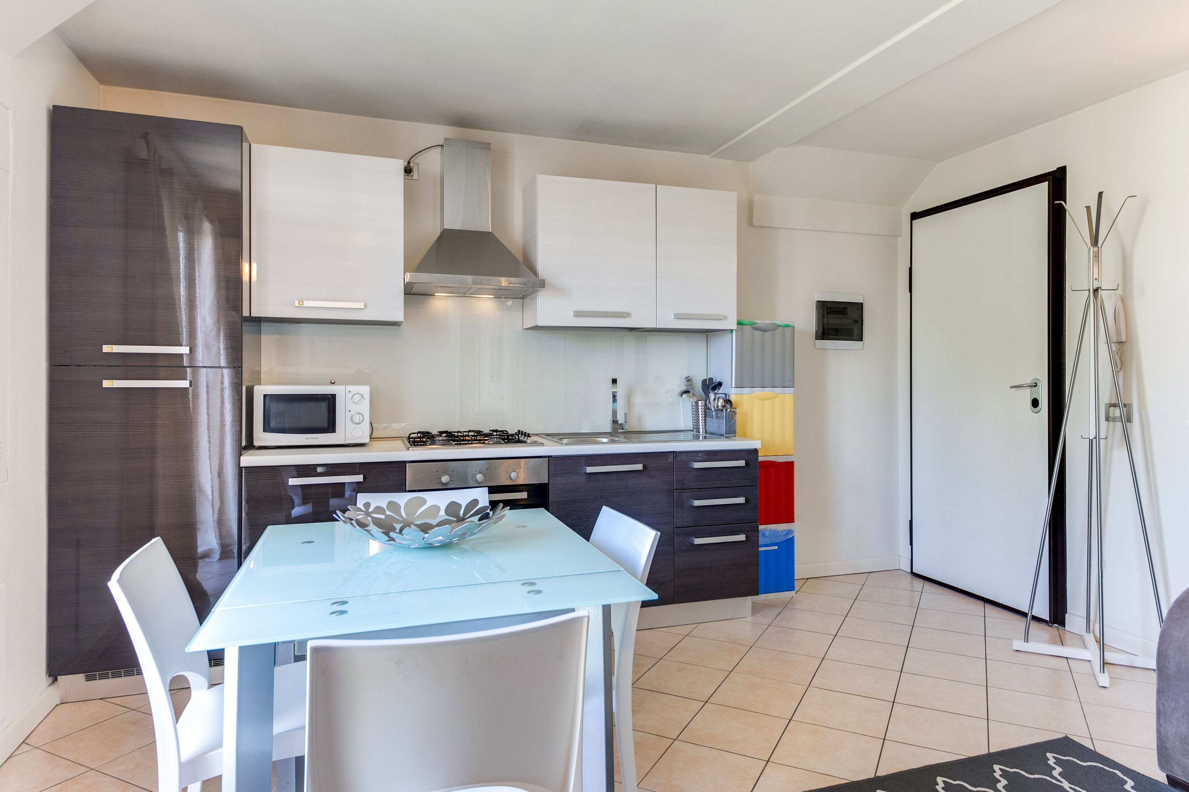 A modern kitchen with white cabinets, a microwave, a gas stove, and a dining table with chairs.