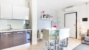 A modern kitchen with white cabinets, a glass dining table, and a coffee machine.
