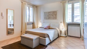 Une chambre à coucher avec un grand lit, une table de chevet, un miroir et une fenêtre avec des rideaux.