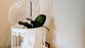 A white birdcage with a butterfly decoration and a white orchid plant.