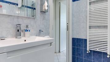 A modern bathroom with a white vanity, a large mirror, and a towel rack.