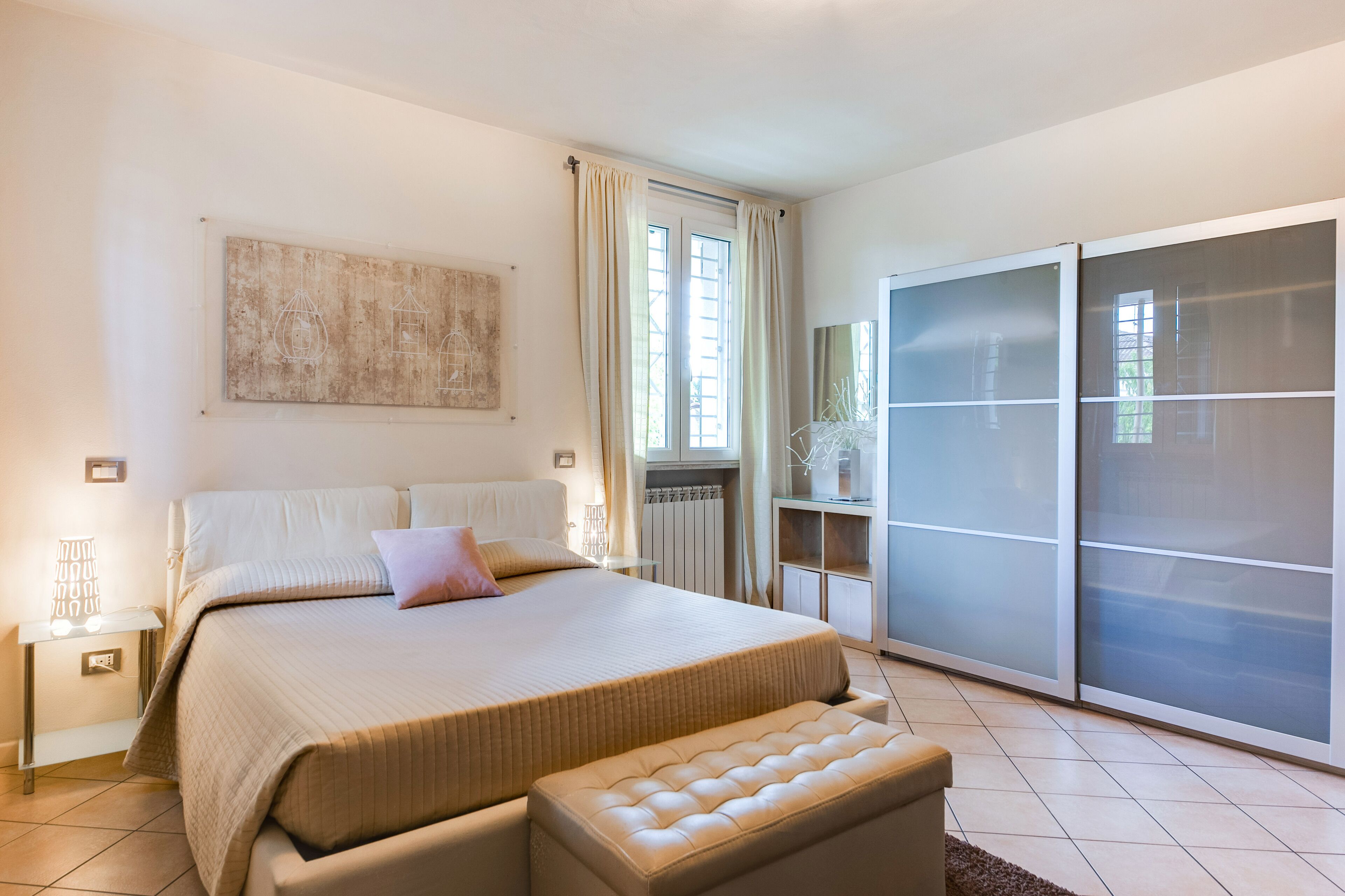 Un dormitorio con una cama grande, una mesita de noche, un armario y una ventana con cortinas.