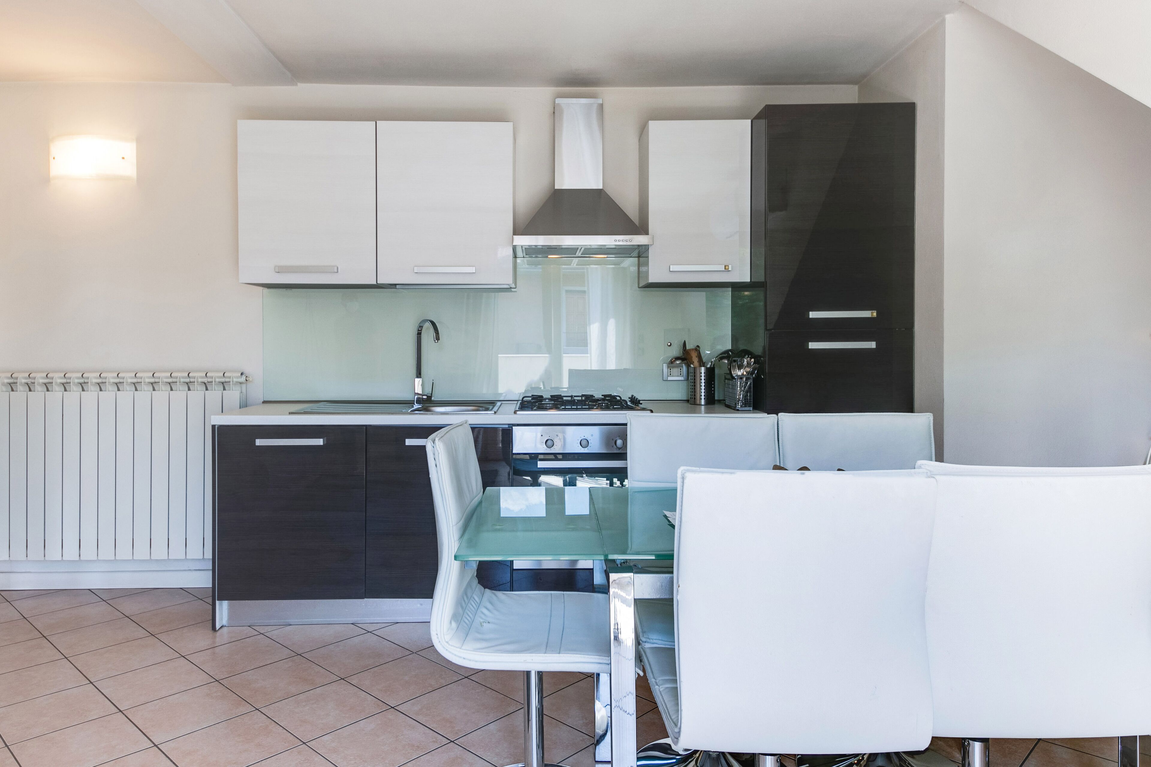 A compact kitchen with white cabinets, a gas stove, and a glass dining table.