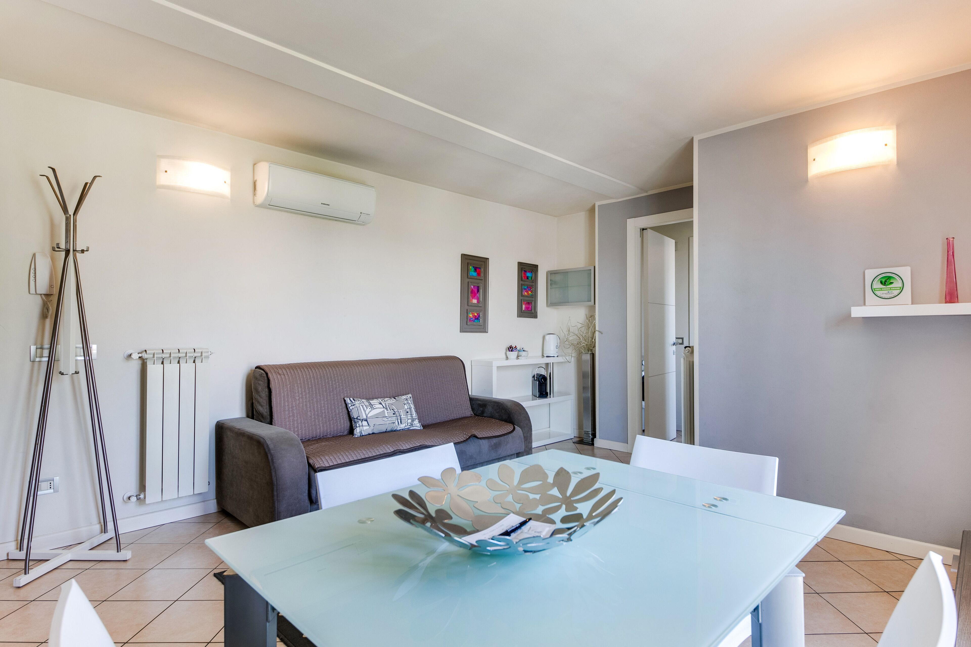 A modern living room with a sofa, a dining table, and a radiator.