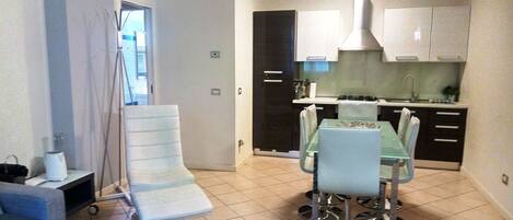 Un espace de vie compact comprenant un coin repas, une kitchenette et un petit coin salon.