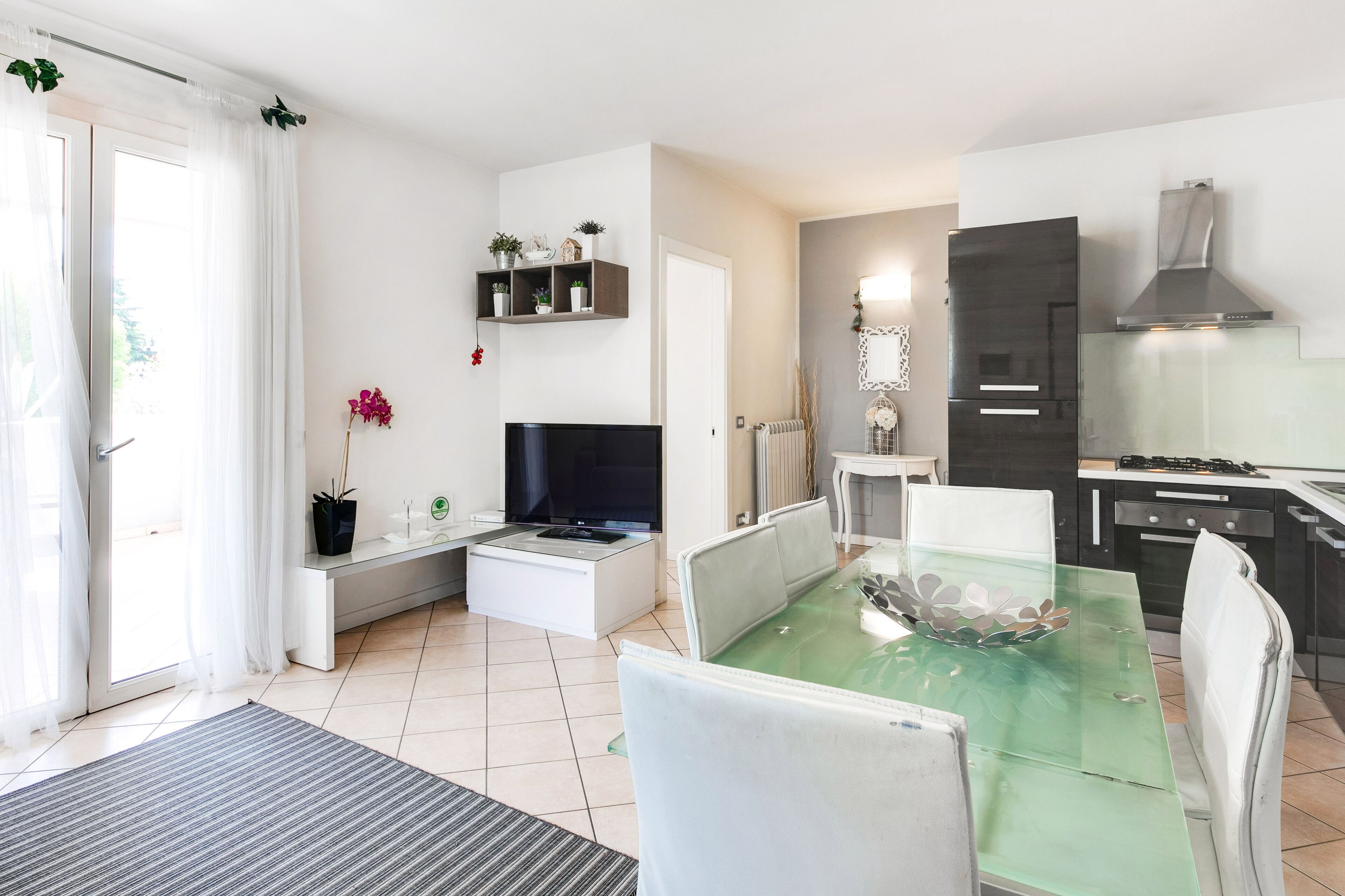 Una cocina moderna con estufa integrada, un comedor con mesa de vidrio y un conjunto de asientos.