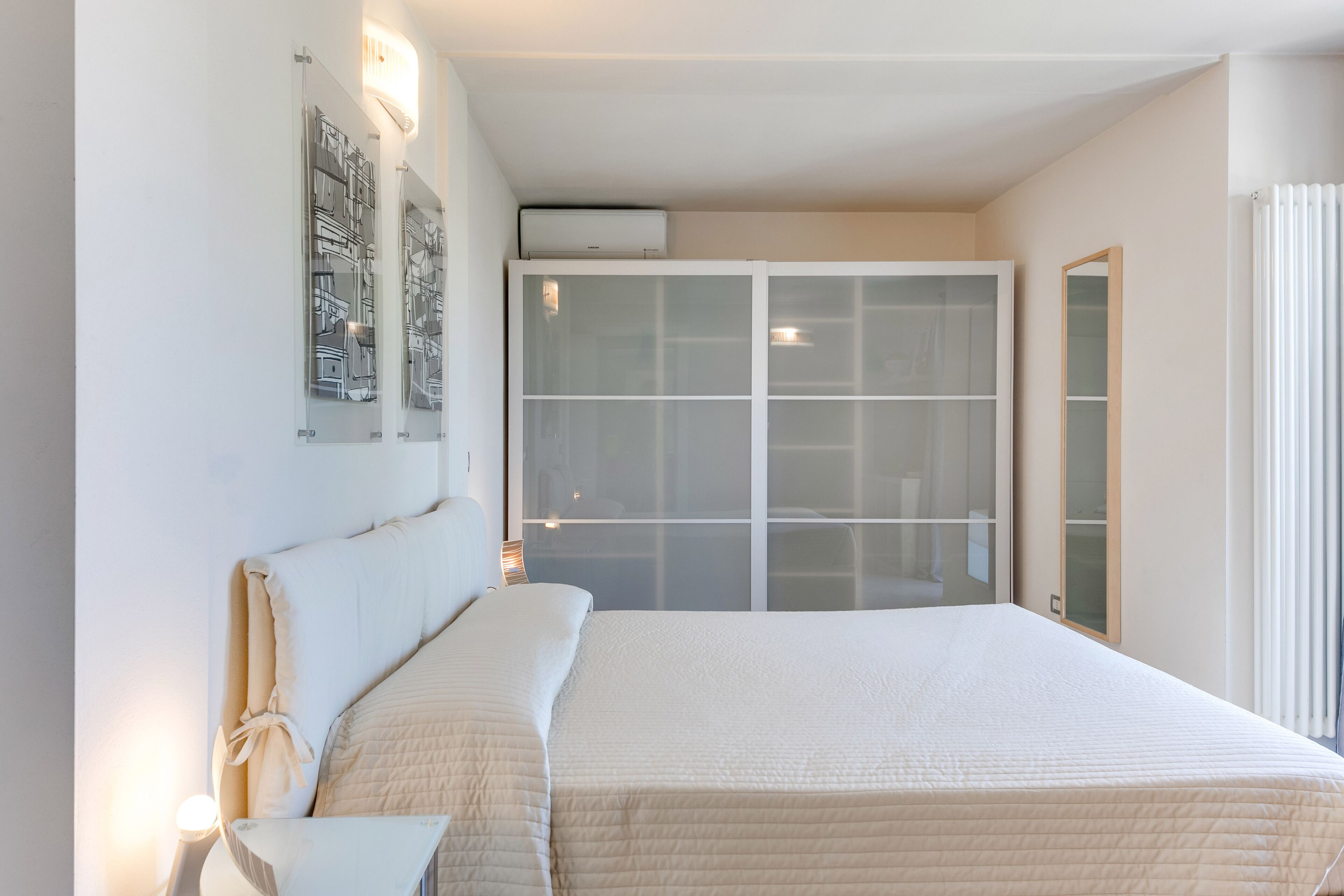 Quarto com uma cama grande, um guarda-roupa e um ar-condicionado fixado na parede.