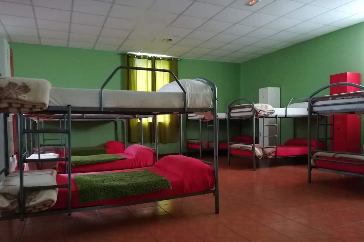 Un dormitorio con literas, paredes verdes y suelo de baldosas.