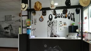 Una reception con un portatile, una parete con cappelli e un murale.