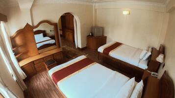 A hotel room with two beds, a wooden dresser, a mirror, a television, and a small cabinet.