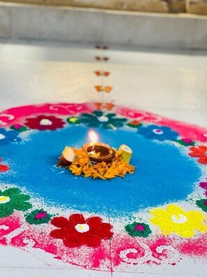 A colorful rangoli with a lit diya in the center. - Hotel Bodhiz (Kathmandu)