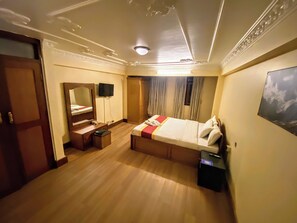 A hotel room with a bed, a desk, a mirror, a television, and a wardrobe. - Hotel Bodhiz (Kathmandu)