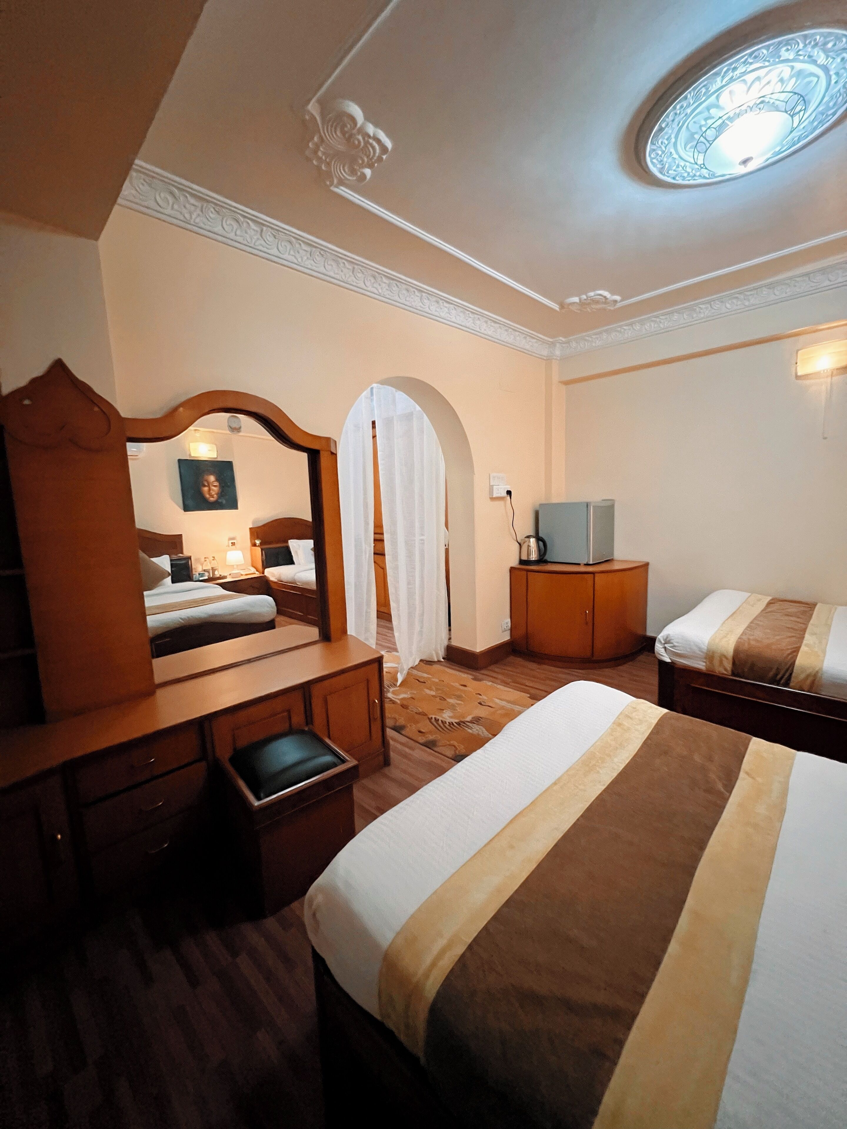 Habitación de hotel con cama, escritorio, espejo, televisor y armario.