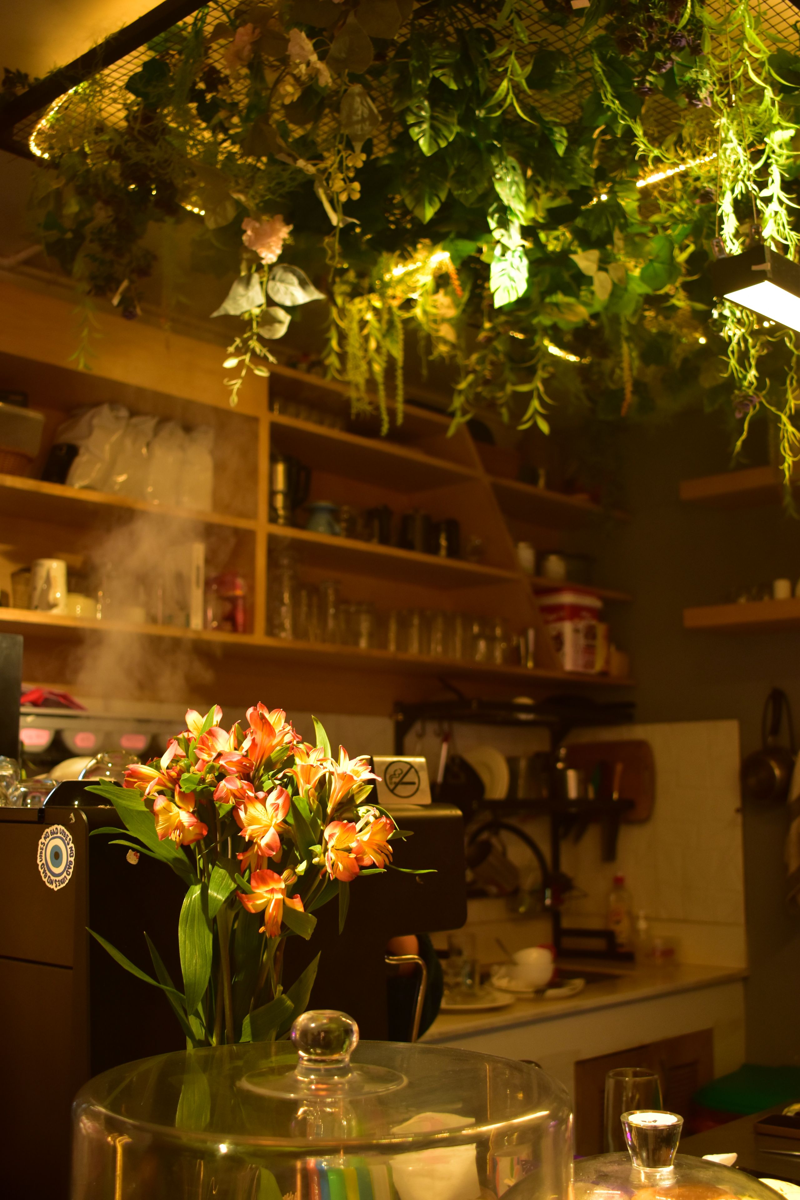 A kitchen with a glass-top table, a coffee machine, and a variety of kitchen utensils.