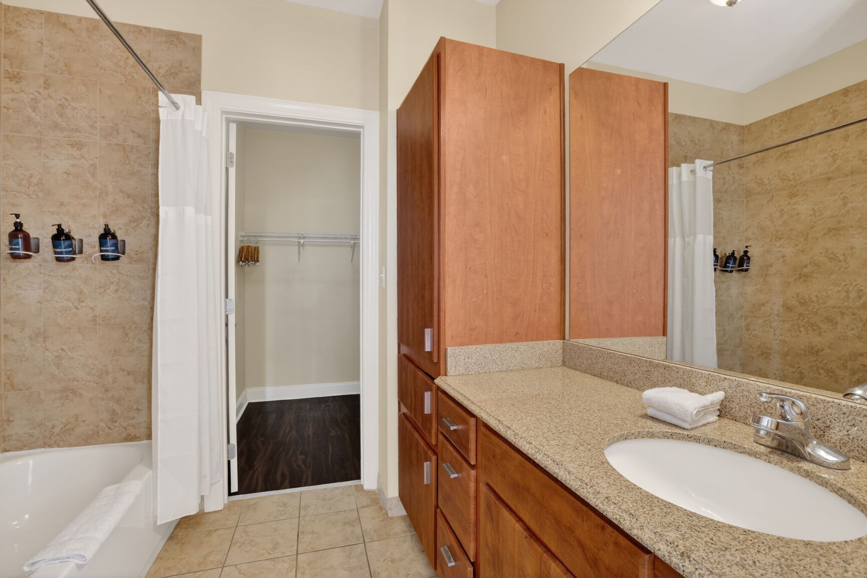 A bathroom with a wooden vanity, a large mirror, a bathtub, and a shower area.