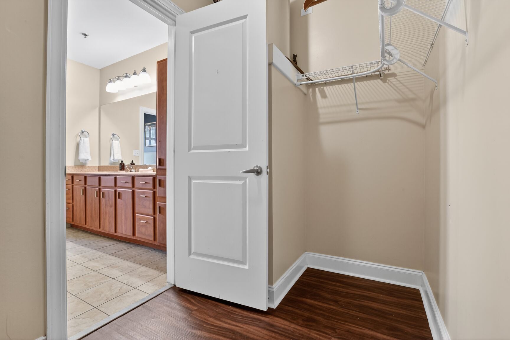 A hallway with a white door, wooden cabinets, and a tiled floor.