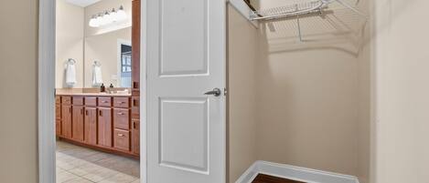 A hallway with a white door, wooden cabinets, and a tiled floor.