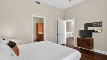 A bedroom with a bed, a dresser, a television, and a mirror.