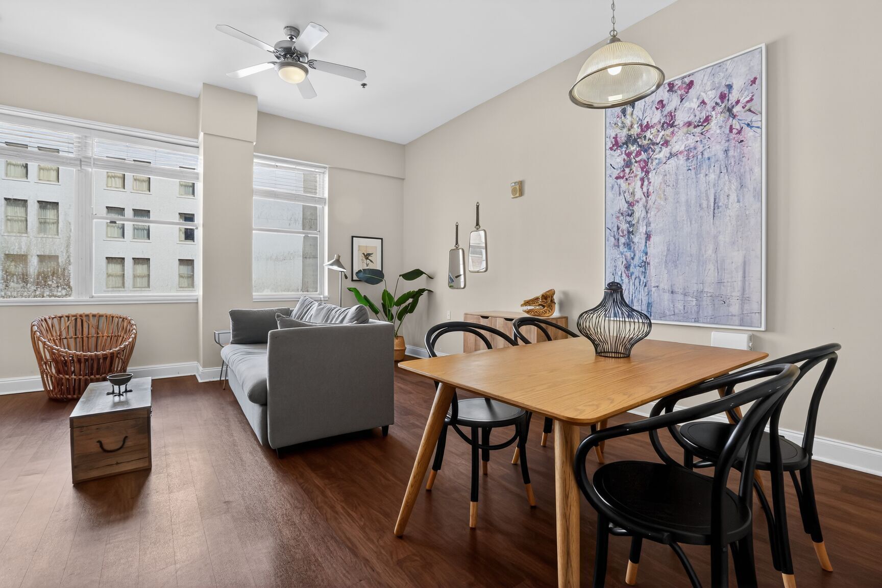 A modern living room with a sofa, dining table, chairs, and a large window.