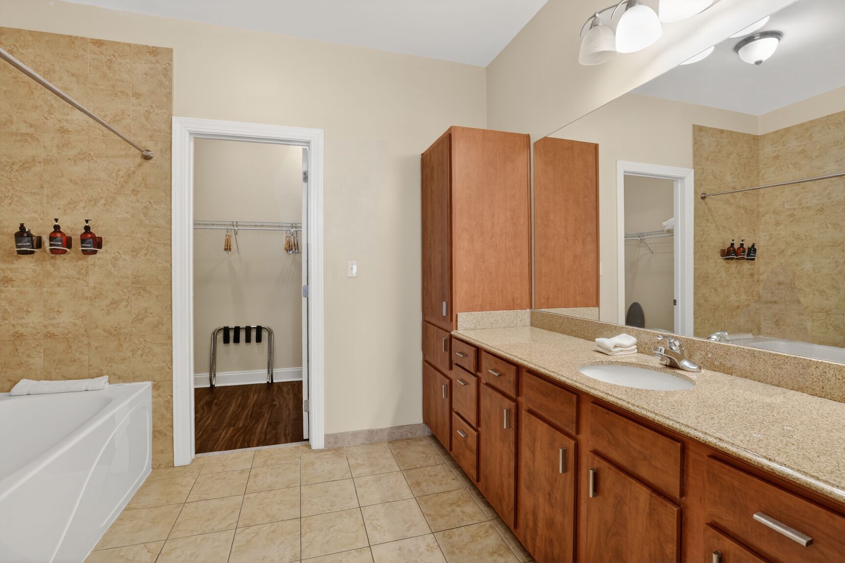 A bathroom with a double sink, wooden cabinets, a large mirror, and a shower area.