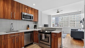 Una cocina moderna con armarios de madera, electrodomésticos de acero inoxidable y vistas a la ciudad a través de amplias ventanas.