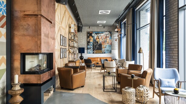 A modern living room with a fireplace, leather sofas, and a large abstract painting on the wall.
