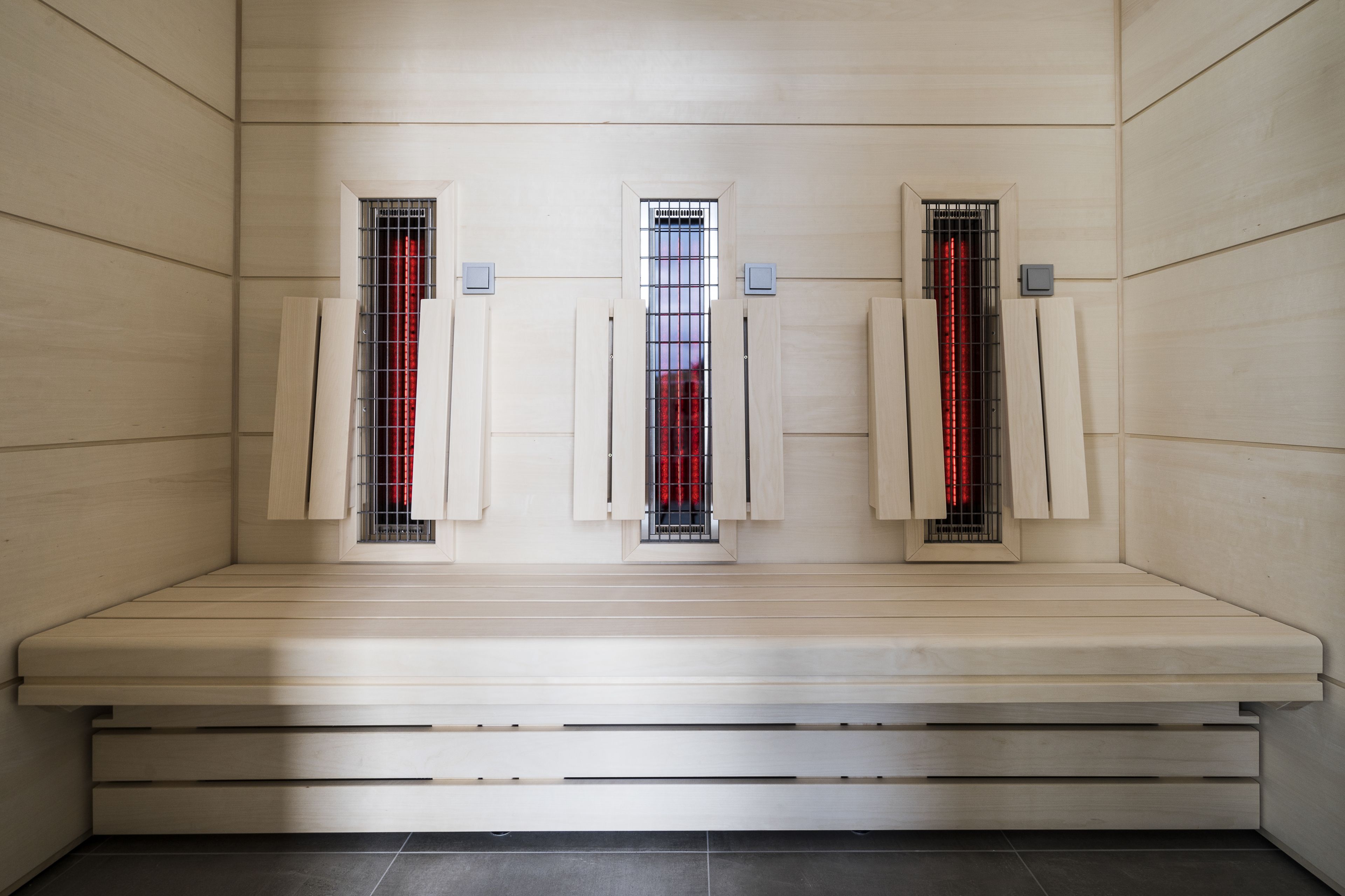 A sauna with three benches, each with a window and a control panel.