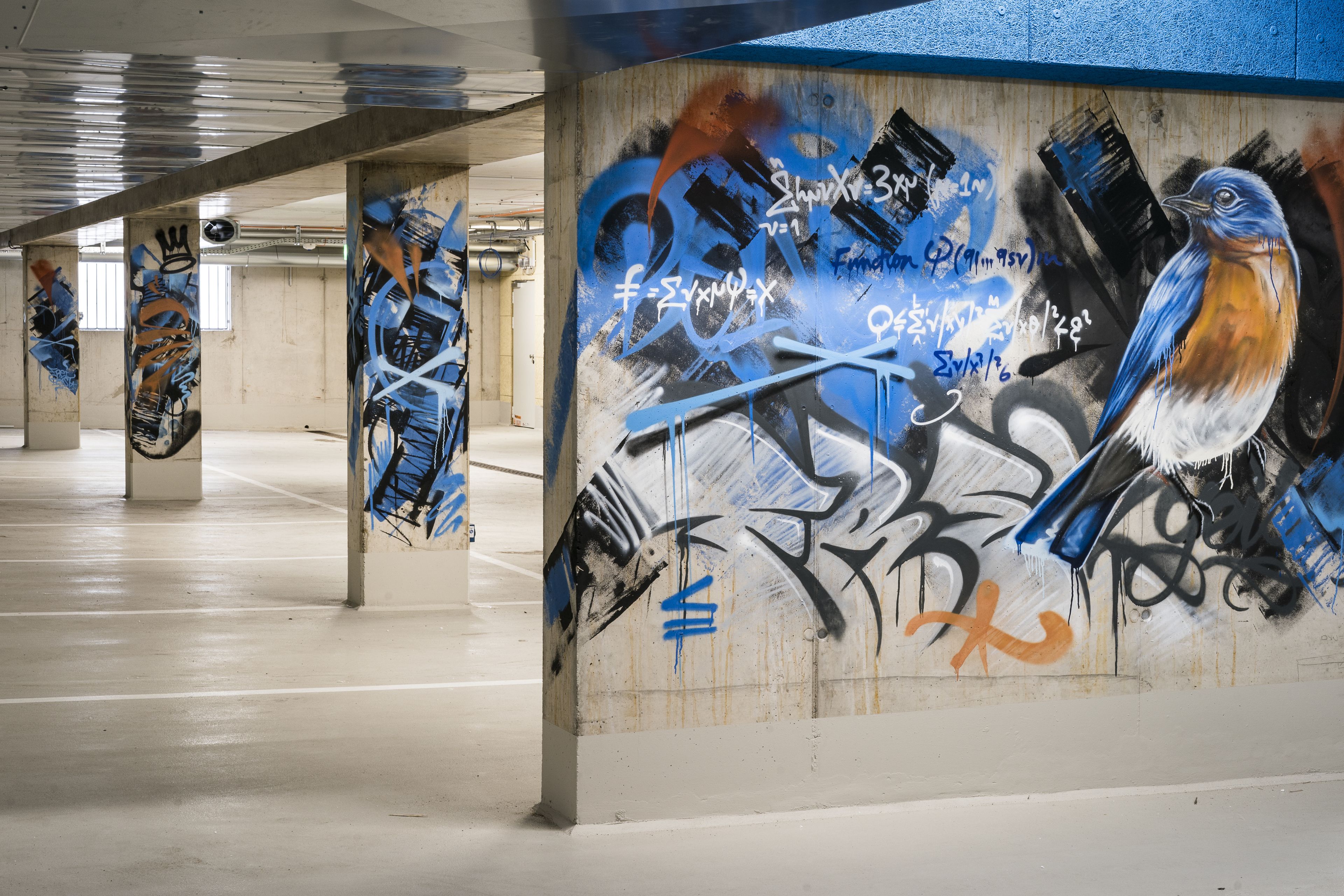 An indoor parking garage with graffiti on the walls and pillars.