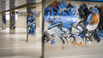Eine überdachte Parkgarage mit Graffiti an Wänden und Säulen.