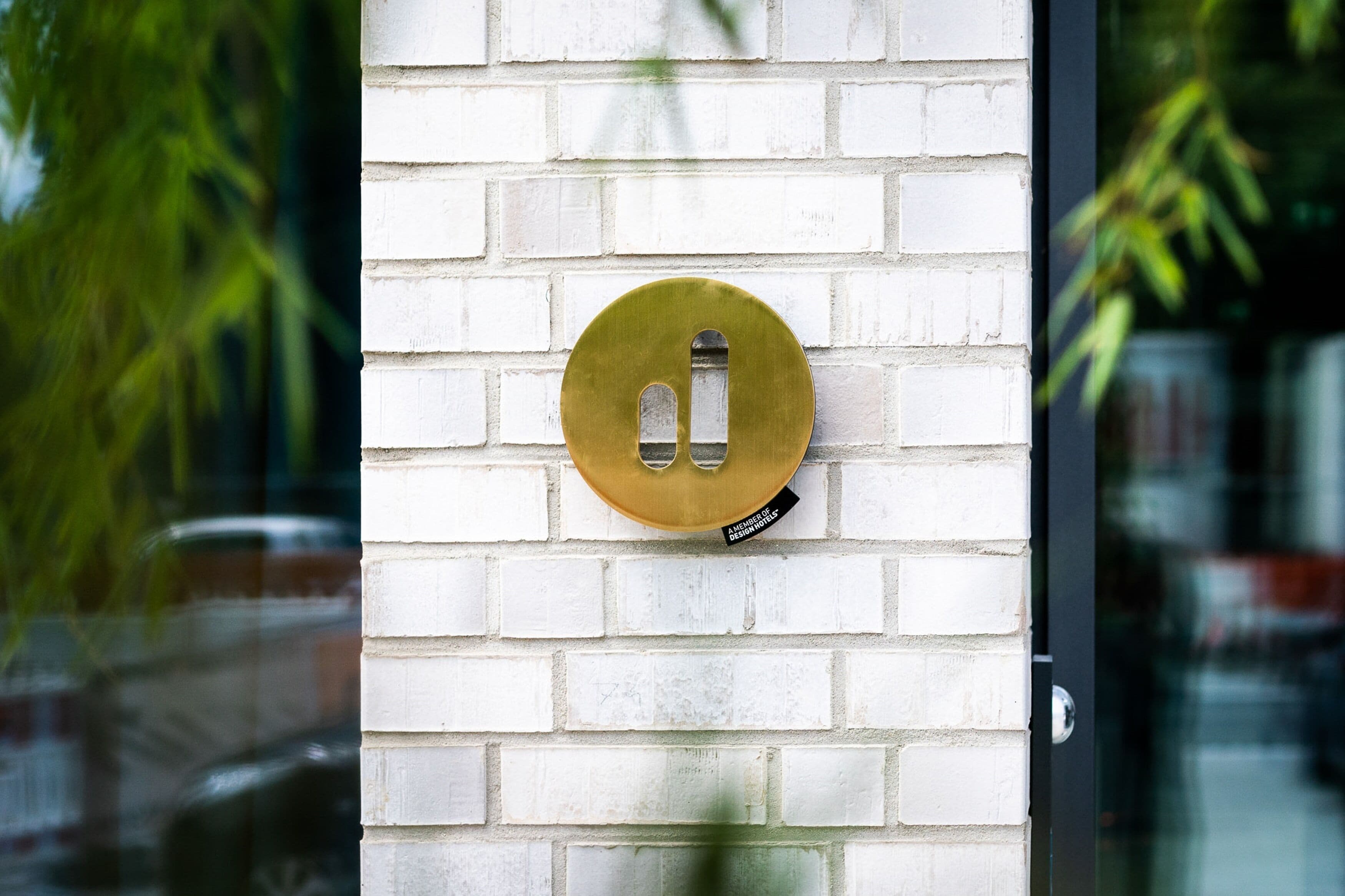 A brass doorbell on a white brick wall.