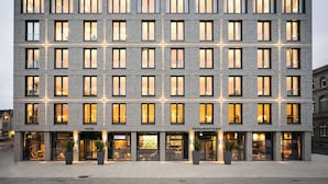 A multi-story hotel with a modern brick facade, large windows, and a ground-level restaurant and bar.