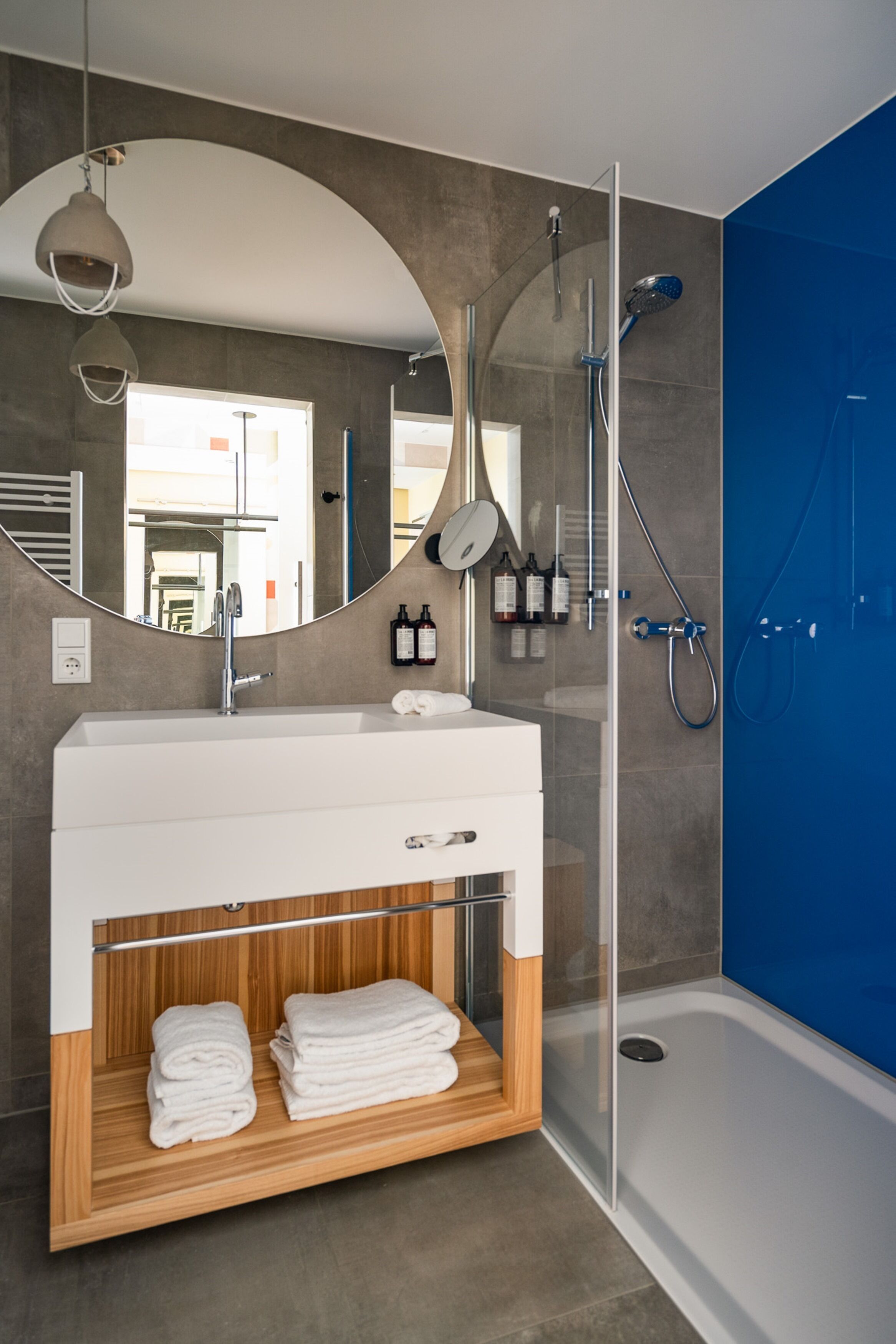 Een moderne badkamer met een grote spiegel, een witte wastafel en een douchehoek.