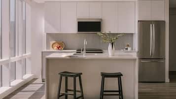 A modern kitchen with a central island, stainless steel appliances, and a large window.