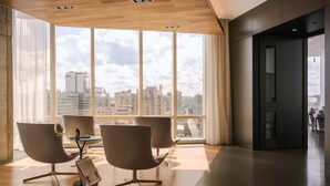 Un interior moderno con amplias ventanas, techo de madera y sillas contemporáneas.