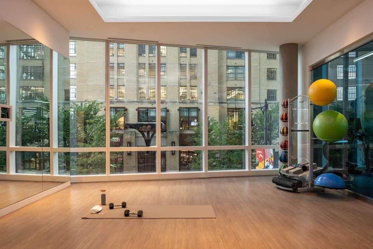 A spacious room with large windows, exercise equipment, and a yoga mat.