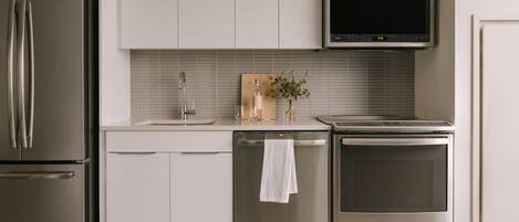 A modern kitchen with stainless steel appliances, a built-in microwave, and a tiled backsplash.