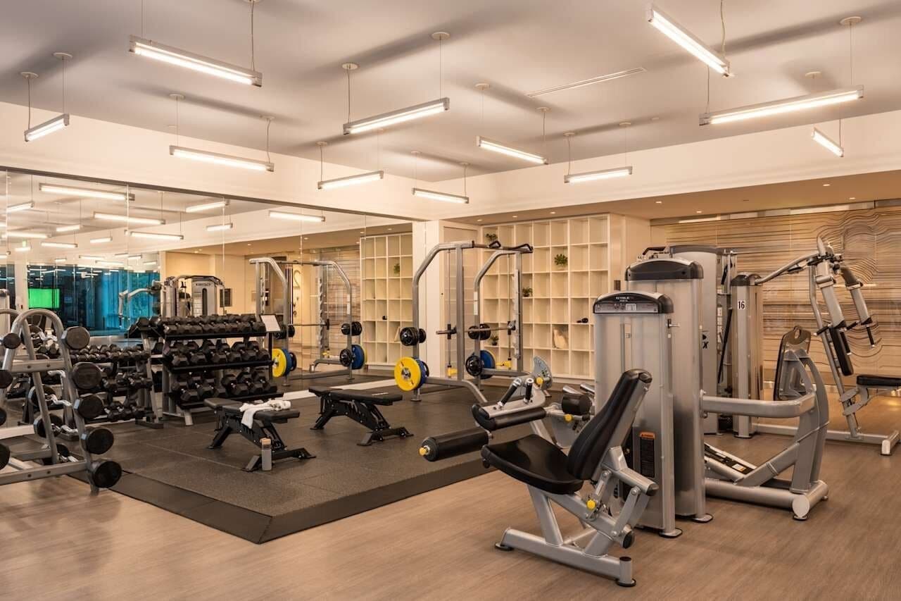 A gym with various exercise equipment, mirrored walls, and a clean, organized layout.