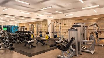A gym with various exercise equipment, mirrored walls, and a clean, organized layout.