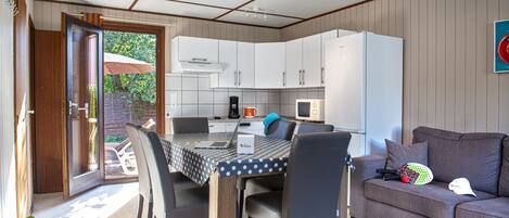 Eine kleine Küche mit Esstisch, Stühlen, einem Kühlschrank und einer Couch.