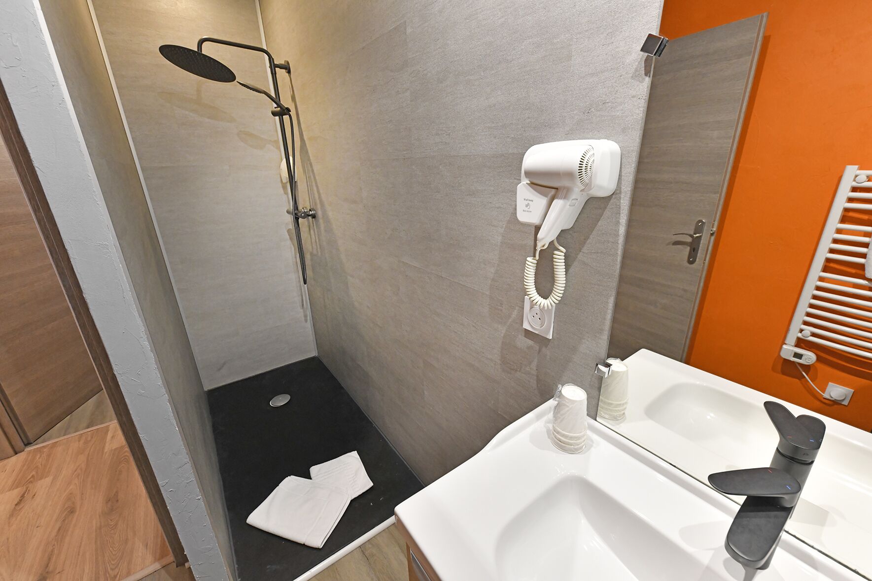 Une salle de bain moderne équipée d’une douche, d’un sèche-cheveux, d’une serviette et de toilettes.