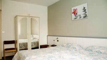 A bedroom with a bed, a wardrobe, two chairs, and a wall-mounted artwork.