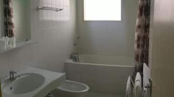 A bathroom with a bathtub, a toilet, and a sink.