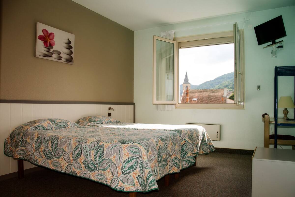 Une chambre à coucher avec un lit, une fenêtre, un téléviseur et un tableau au mur.