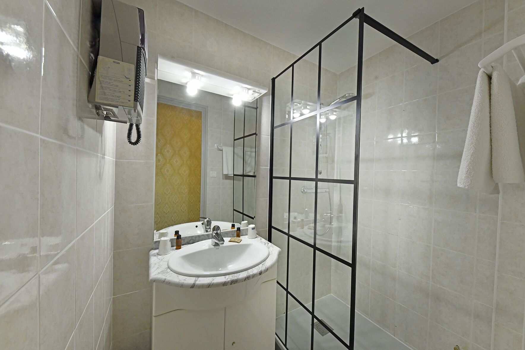 Un bany amb un rentapans blanc, un mirall i una cabina de dutxa de vidre.