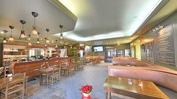 A spacious bar area with multiple seating options, including booths and tables, and a television screen mounted on the wall.