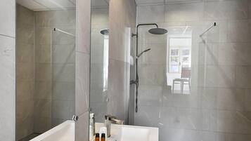Un baño moderno con un espejo grande, dos lavamanos y una zona de ducha.