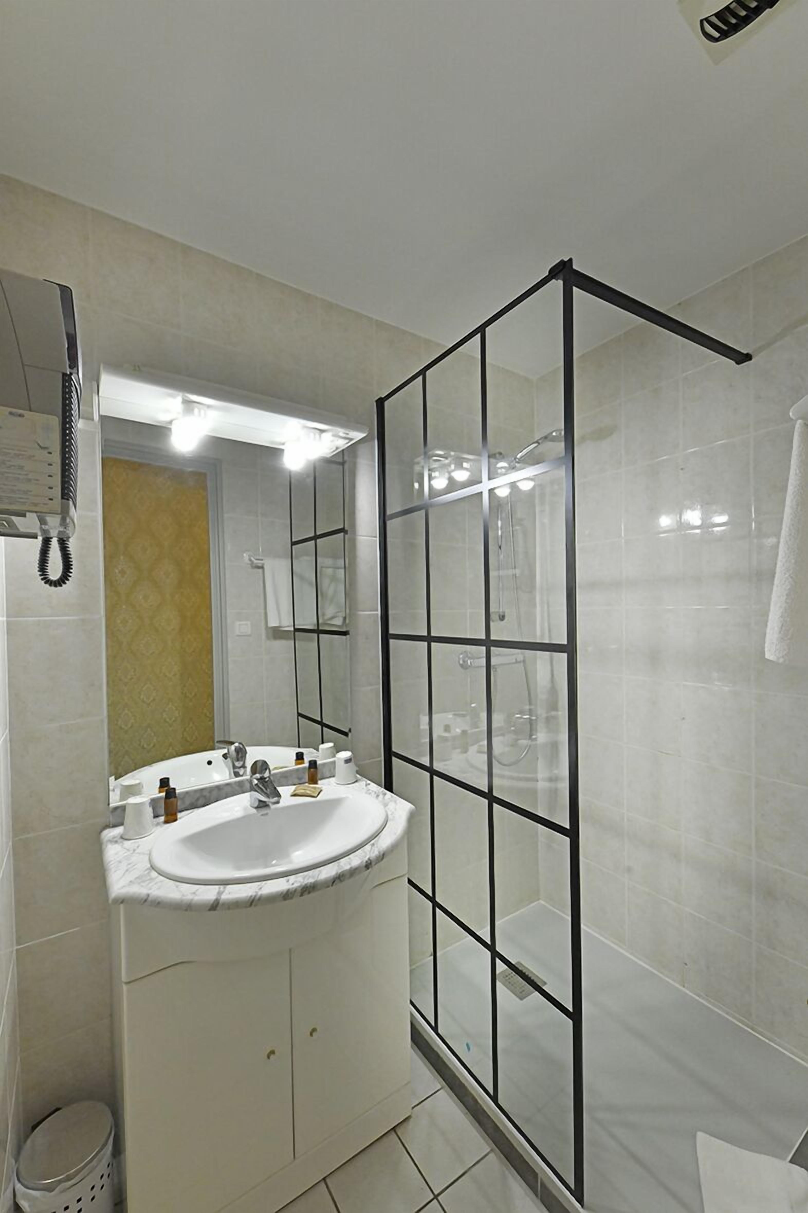 Une salle de bain moderne avec une douche à parois de verre, un lavabo blanc et un miroir au-dessus.