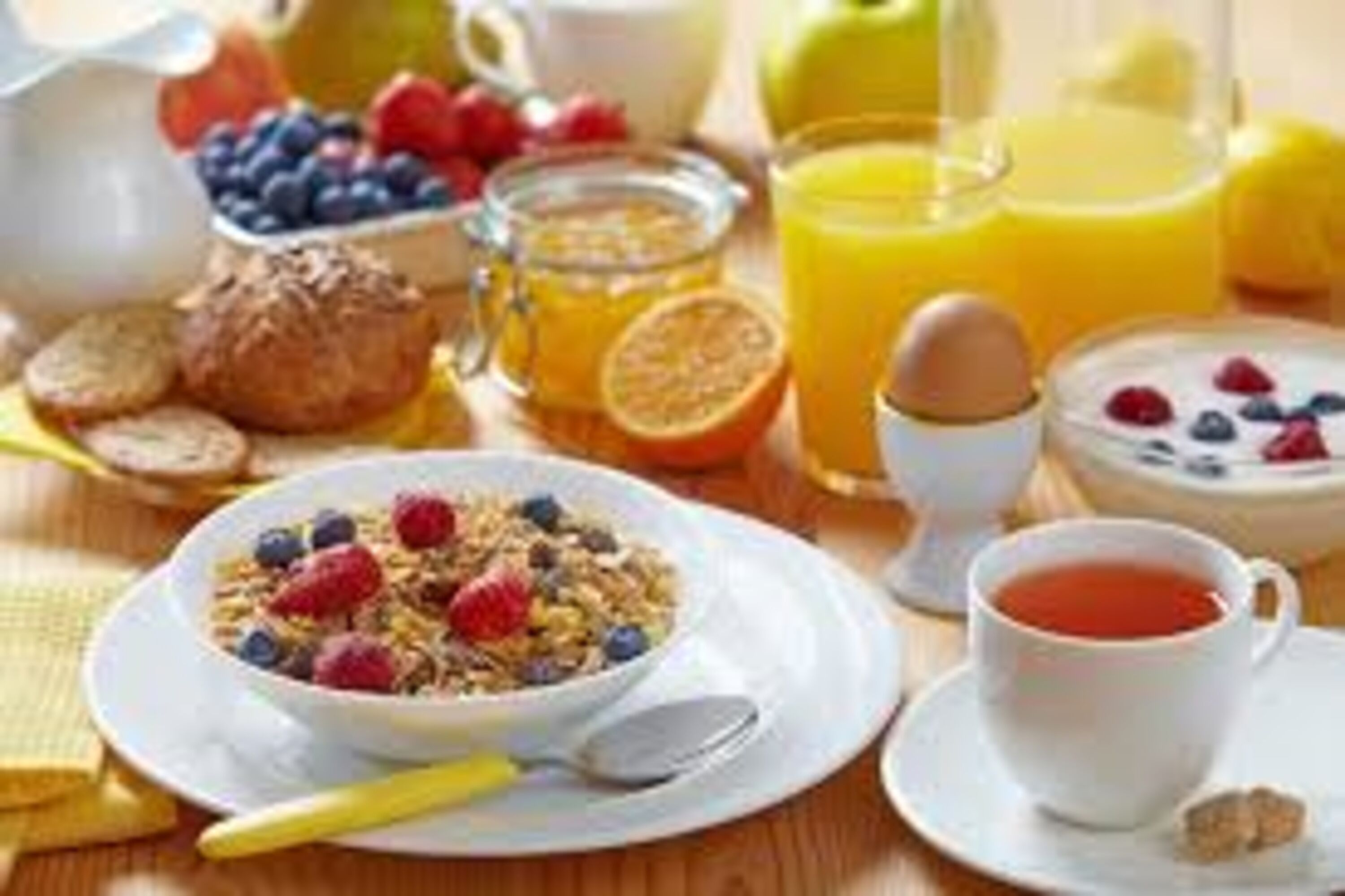 Desayuno con un tazón de cereal, una taza de té y un vaso de jugo de naranja.