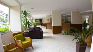 Um hall amplo com balcão de recepção, assentos confortáveis e plantas em vasos.